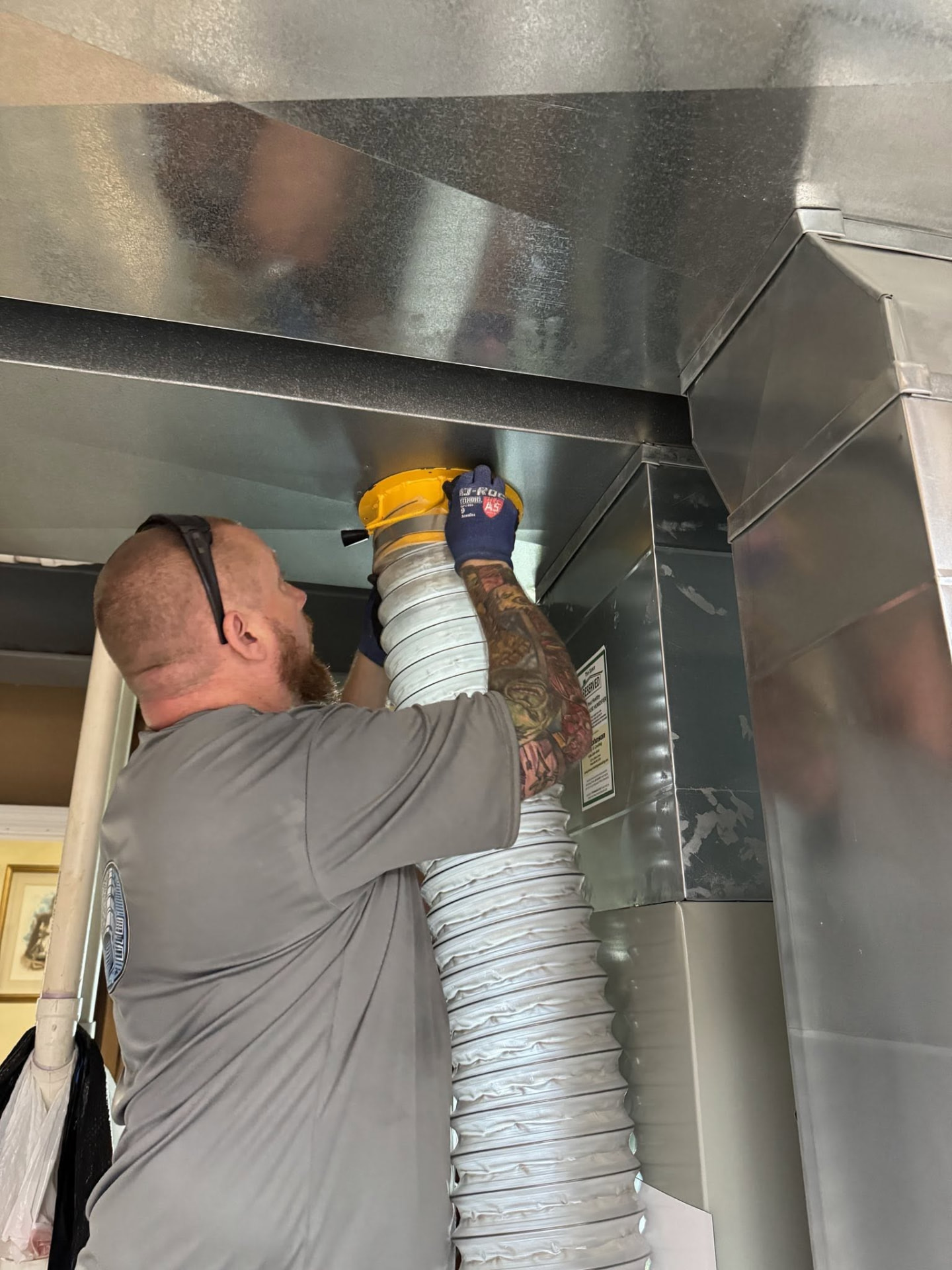 Technician connecting the vacuum hose to the duct trunk line